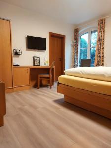 a bedroom with a bed and a desk with a television at Gästehaus Niemerg in Warendorf