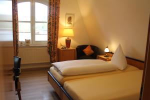 una camera con un letto e una sedia e una finestra di Gästehaus Niemerg a Warendorf