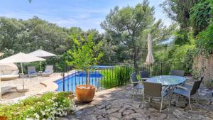 eine Terrasse mit einem Tisch, Stühlen und einem Pool in der Unterkunft Casa Oliver in El Port