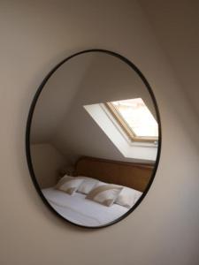 um espelho numa parede com uma cama e uma janela em VAGABONDO PETIT MAISON em Caserta