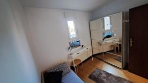 Habitación blanca pequeña con escritorio y espejo. en Acogedora Habitación Centro Bilbao, en Bilbao