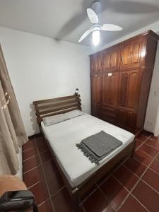 a bedroom with a bed and a wooden cabinet at Apartamento Guaruja Enseada in Guarujá