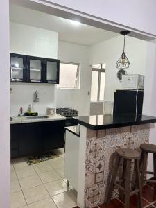 una cocina con encimera negra y fregadero en Apartamento Guaruja Enseada, en Guarujá
