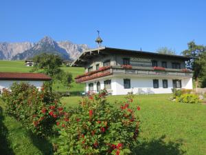 un gran edificio blanco con flores rojas en un campo en Chalet Glockenhof, en Walchsee