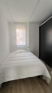 a large white bed in a room with a window at Exyca Metropolitano in Madrid