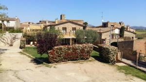 a house in a village with bushes and flowers at Casa Rural Can Ginesta in San Felíu de Boada