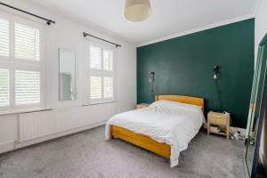 1 dormitorio con 1 cama con pared verde en Cosy tranquil semi-detach house, en Beckenham