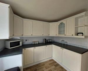 eine weiße Küche mit weißen Schränken und einer Mikrowelle in der Unterkunft Craig View Fishermans Cottage nr Harbour and Beach in Barmouth + 10 Fotos