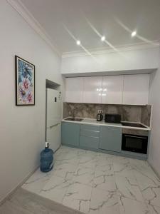 eine Küche mit weißen Schränken und einem Kühlschrank in der Unterkunft Двухкомнатная квартира в жилом доме ЖК Арман/ One-bedroom apartment in Arman residential complex in Atyrau + 3 Fotos