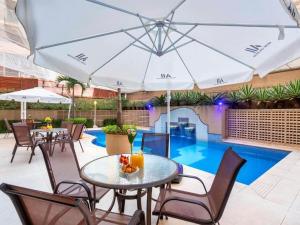 a patio with tables and chairs and a swimming pool at Flat Funchal JK Limpeza Diária, Internet 300mb in Sao Paulo