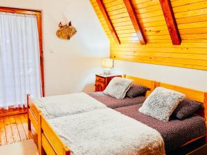two beds in a bedroom with a wooden ceiling at Vikend kuća Dina Vlašić in Vlasic