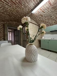 Un jarrón con flores sobre una mesa en una cocina. en 2х кім-й Loft на площі Філармонії by Willox, en Chernivtsi
