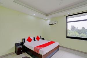 OYO Flagship Shree Shyam Kripa Hotel And Restaurant في كانبور: غرفة نوم بسرير ومخدات حمراء ونافذة
