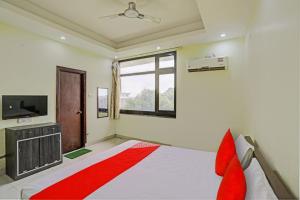 a bedroom with a bed and a tv and a window at OYO Flagship Shree Shyam Kripa Hotel And Restaurant in Kānpur