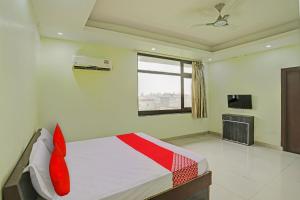 a bedroom with a bed with red pillows and a television at OYO Flagship Shree Shyam Kripa Hotel And Restaurant in Kānpur