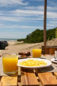 einen Tisch mit einem Teller Essen und zwei Gläsern Orangensaft in der Unterkunft Domos Park in Mar de las Pampas