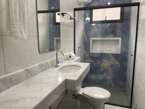 y baño con lavabo, aseo y espejo. en Pousada Favo de Mel - Unidade 2 en Guarujá
