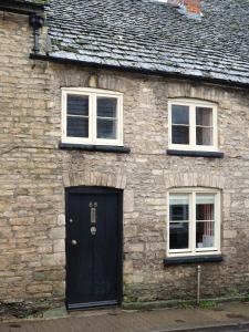a brick house with a black door and two windows at Townhouse Suites- Abbey Row in Malmesbury