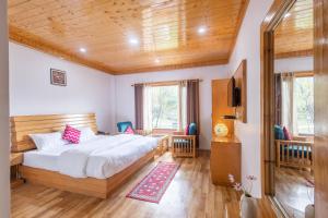 um quarto com uma cama grande e um tecto de madeira em Aroha Residency- A Countryside Resort em Manali