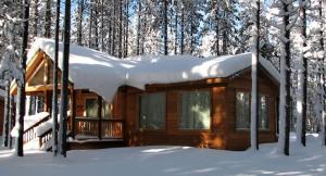 a log cabin with snow on the roof in the woods at Willamette Pass Inn & Chalets in Odell Lake