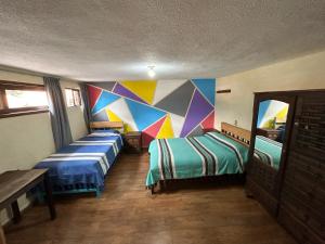 2 camas en una habitación con una pared colorida en Hostel Casa De Yagil en San Cristóbal de Las Casas