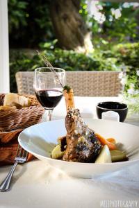 a plate of meat and vegetables with a glass of wine at Logis Hotel Restaurant la Ferme in Avignon