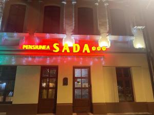 un panneau néon pour un restaurant saada dans un bâtiment dans l'établissement Pensiunea SADA, à Făgăraş