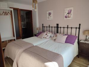 um quarto com uma grande cama branca com almofadas roxas em Alojamiento Rural Tres Palacios em Molina de Aragão