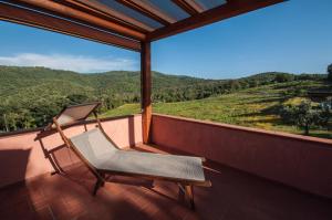 a rocking chair sitting on a balcony with a view at Agriturismo Colle Donatucci in Castagneto Carducci