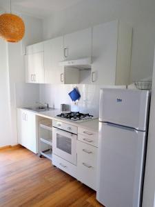 a kitchen with white cabinets and a white refrigerator at Trilo Lorenzo - In centro ed a soli 30 m dal mare in Numana +7 photos