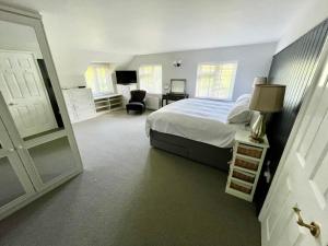 um quarto com uma cama, uma cadeira e uma porta em Seaside Spacious Cosy Cottage On The Edge Of The New Forest em Lymington