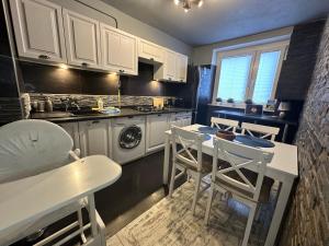 kuchnia z białymi szafkami, stołem i krzesłami w obiekcie Apartment Ustroń w Ustroniu