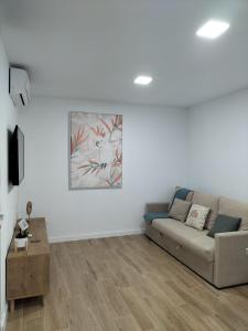 uma sala de estar com um sofá e uma pintura na parede em Apartamento D&L em Costa Del Silencio