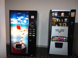 a soda vending machine next to a refrigerator at South Hill Motor Inn in Red Deer