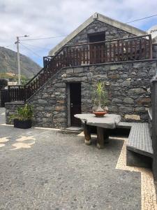 a stone building with a table and a bench at Cozy chalet with ocean view in Seixal