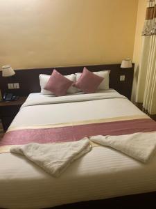 Una cama grande con almohadas rosas y moradas. en Rameshworam Hotel en Katmandú