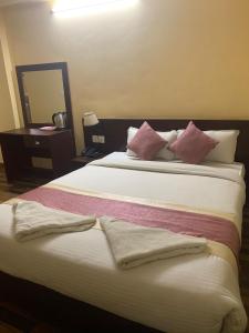 1 dormitorio con 1 cama grande con almohadas rosas y blancas en Rameshworam Hotel, en Katmandú