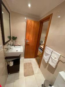 La salle de bains est pourvue d'un lavabo et d'une porte en bois. dans l'établissement Cozy chalet with ocean view, à Seixal