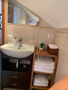W łazience znajduje się umywalka, lustro i ręczniki. w obiekcie Cozy chalet with ocean view w mieście Seixal