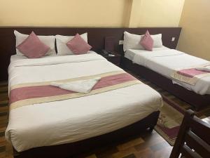 2 Betten in einem Hotelzimmer mit rosa Kissen in der Unterkunft Rameshworam Hotel in Kathmandu