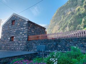 a stone building with a fence next to a mountain at Cozy chalet with ocean view in Seixal