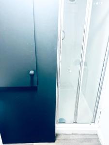 une douche avec un mur bleu et une porte en verre dans l'établissement A room in 2 bedroom house, à Hull