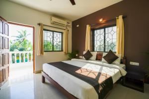 een slaapkamer met een groot bed en een groot raam bij Hotel Pasquina Baga in Baga