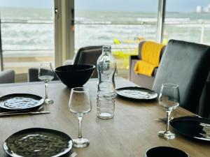a table with glasses and a bottle of water on it at Appartement rénové à neuf avec vue imprenable sur la baie des Sables d Olonne 6 pers in Les Sables-dʼOlonne
