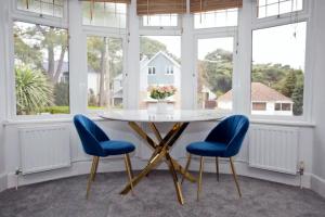 a dining room with a table and two blue chairs at A Piece of Seaside Serenity on the Sandbanks Peninsula in Sandbanks