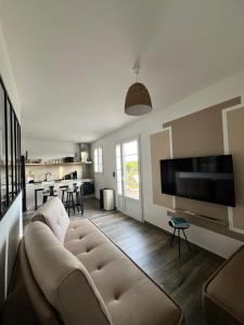 een woonkamer met een bank en een tv bij L Arancera - Sant Anghjulu - Appartement cosy in Penta-di-Casinca