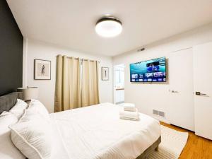 - une chambre blanche avec un lit et une télévision murale dans l'établissement Relaxing 6 BR Oasis with Pool - Lou1, à Los Angeles