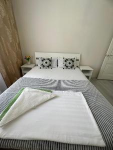 ein Bett mit weißen Laken und Kissen in einem Zimmer in der Unterkunft Двухкомнатная квартира в жилом доме ЖК Арман/ One-bedroom apartment in Arman residential complex in Atyrau