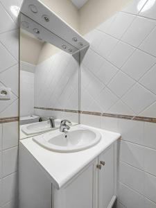 een witte badkamer met een wastafel en een spiegel bij La Douceur Richelieuse in Richelieu