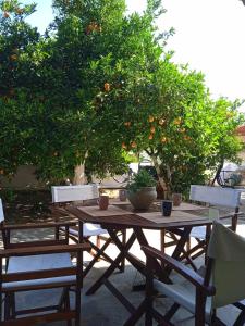 un tavolo in legno con sedie di fronte a un albero di arancio di Margaritas Cottage a Nauplia